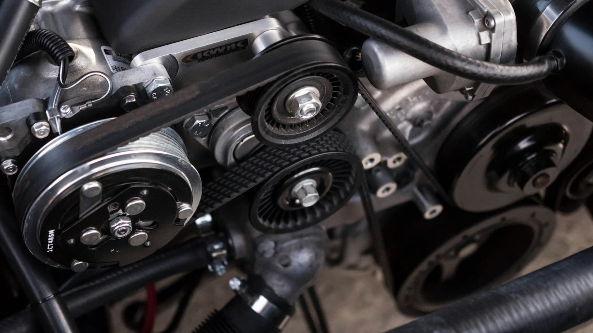 Close-up of an automotive engine with drive belts, pulleys and electrical components
